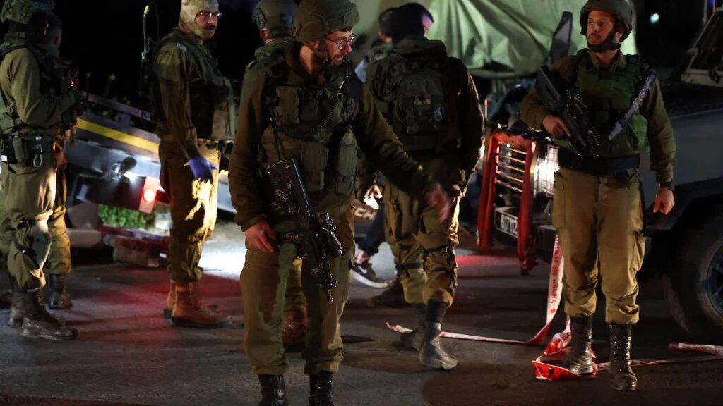 Israeli soldiers gather at the site of a ramming attack near the town of Beit Ummar, north of Hebron city in the occupied West Bank, on 1 April 2023 (AFP)