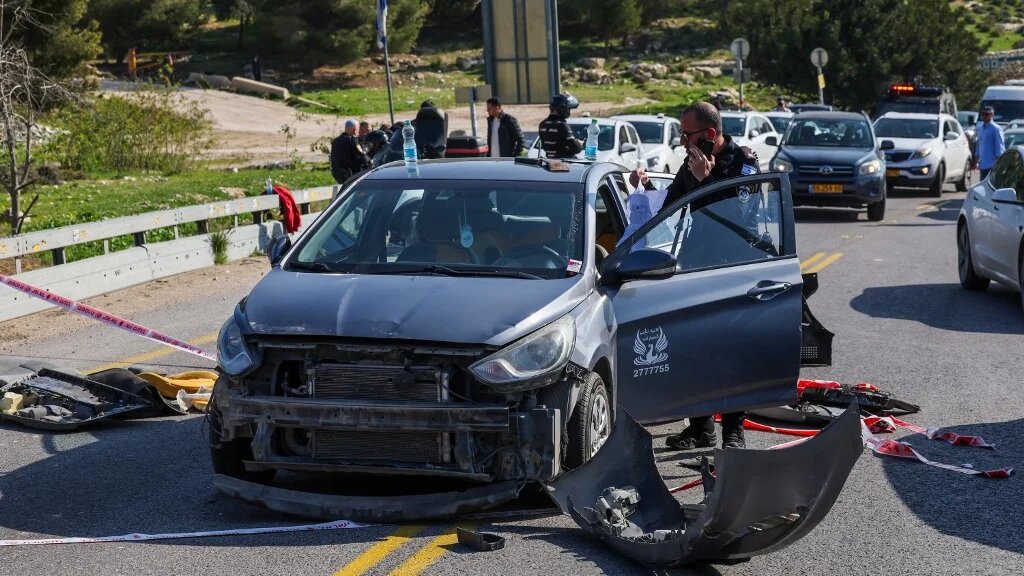 A member of the Israeli security forces inspects a damaged car at the scene of a shooting near the Maale Adumim settlement in East Jerusalem on 22 February 2024 (Ahmad Gharabli/AFP)