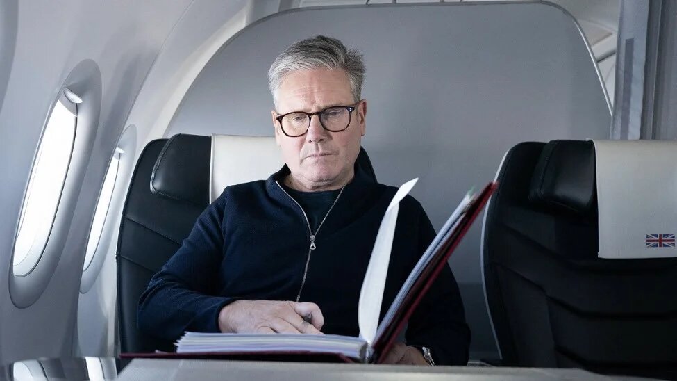 Keir Starmer poses for a photograph as he works whilst travelling on a government aeroplane on 17 November (Stefan Rousseau/AFP)