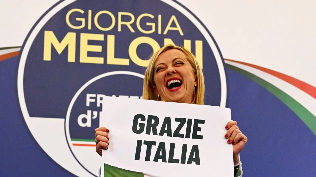 Giorgia Meloni, leader of Italian far-right party Fratelli d'Italia (Brothers of Italy), holds a placard reading 'thank you Italy', at her campaign headquarters in Rome, on 26 September 2022 (AFP)