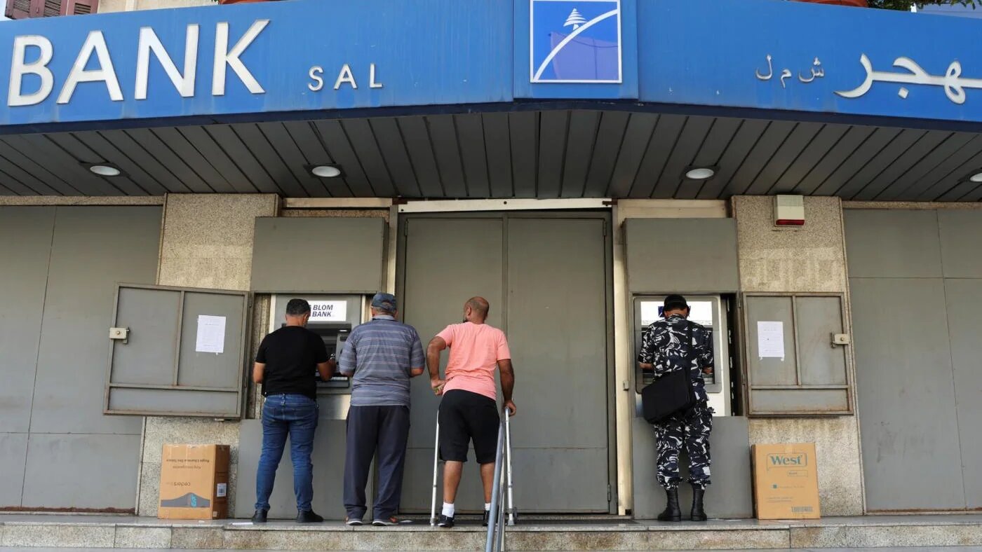 Des personnes utilisent les distributeurs automatiques d’une agence Blom Bank fermée, à Beyrouth, le 20 septembre 2022 (Reuters)
