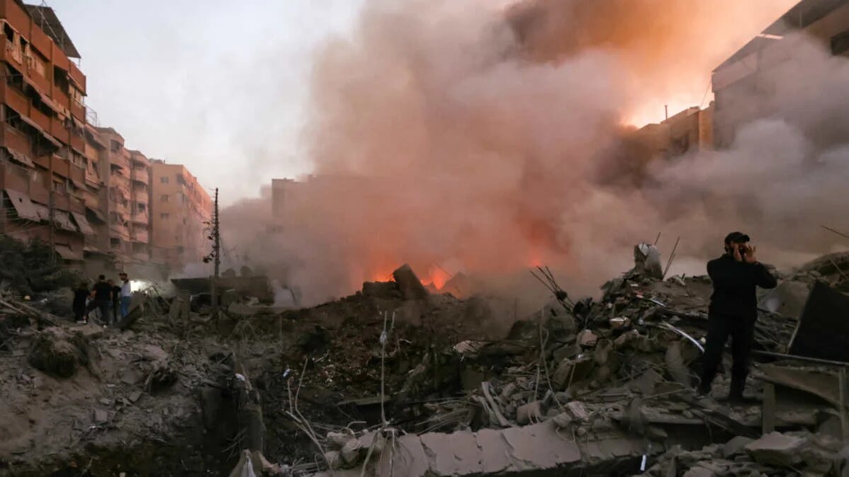 People and rescuers gather near the smouldering rubble of a building destroyed in an Israeli air strike in the Haret Hreik neighbourhood of Beirut's southern suburbs on 27 September, 2024 (Ibrahim Amro/AFP)