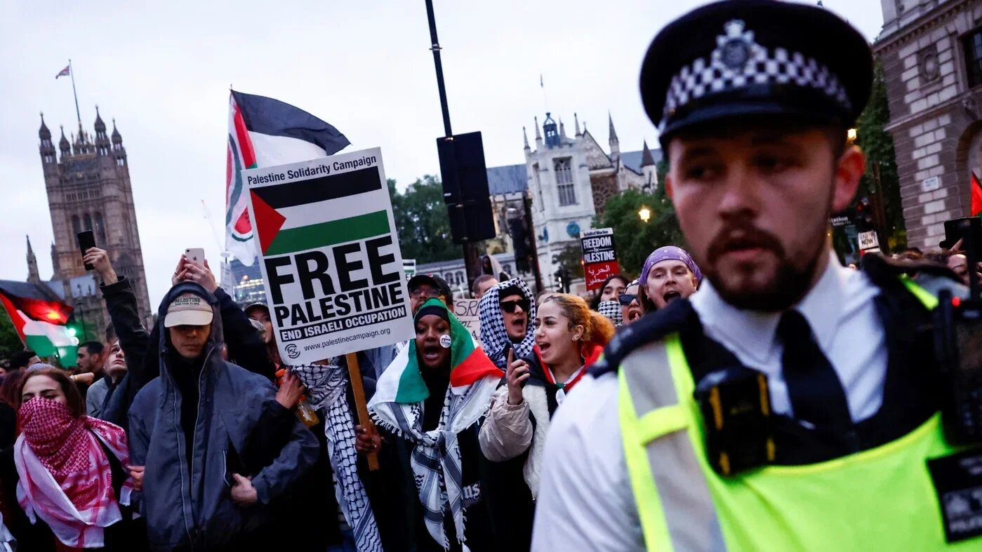 Pro-Palestinian supporters chant slogans behind a Metropolitan Police officer during 'End the genocide' rally in central London, on 28 May 2024 (AFP)