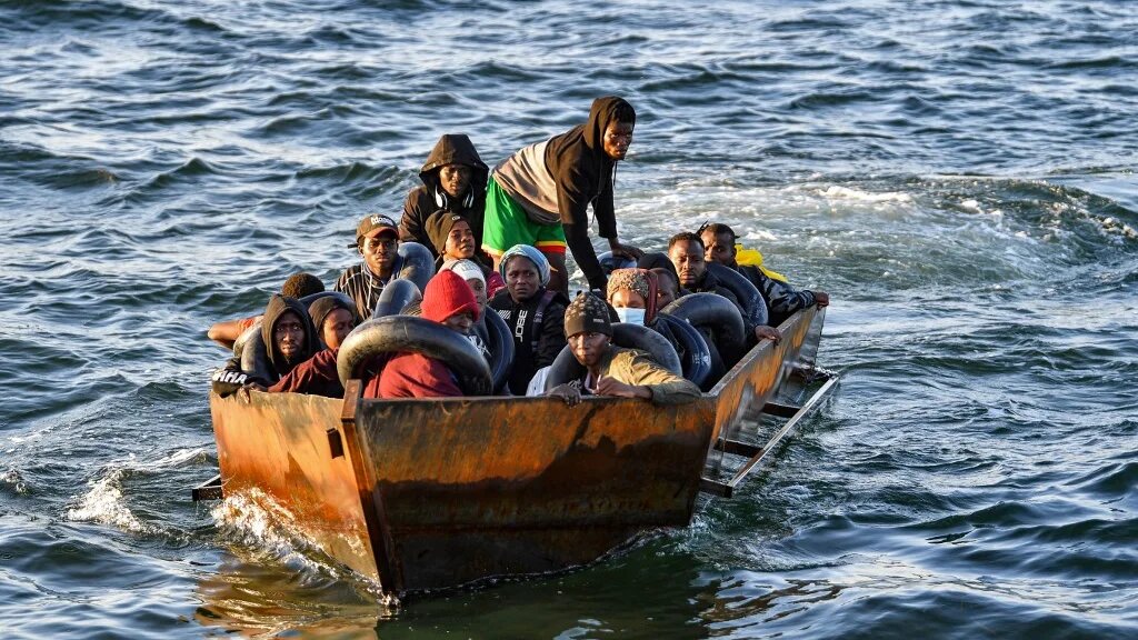Migrants in a makeshift boat after being found heading for Italy by Tunisian authorities about 50 miles off the coast of Tunisia's city of Sfax on 4 October 2022 (AFP)