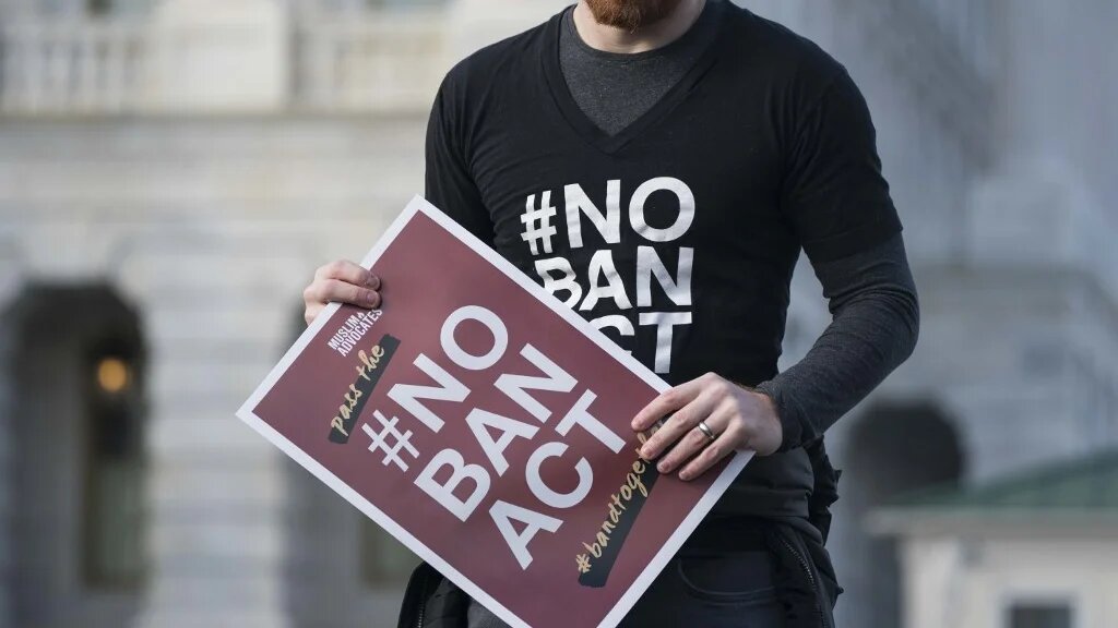 A protester carries a 'No Ban Act' placard