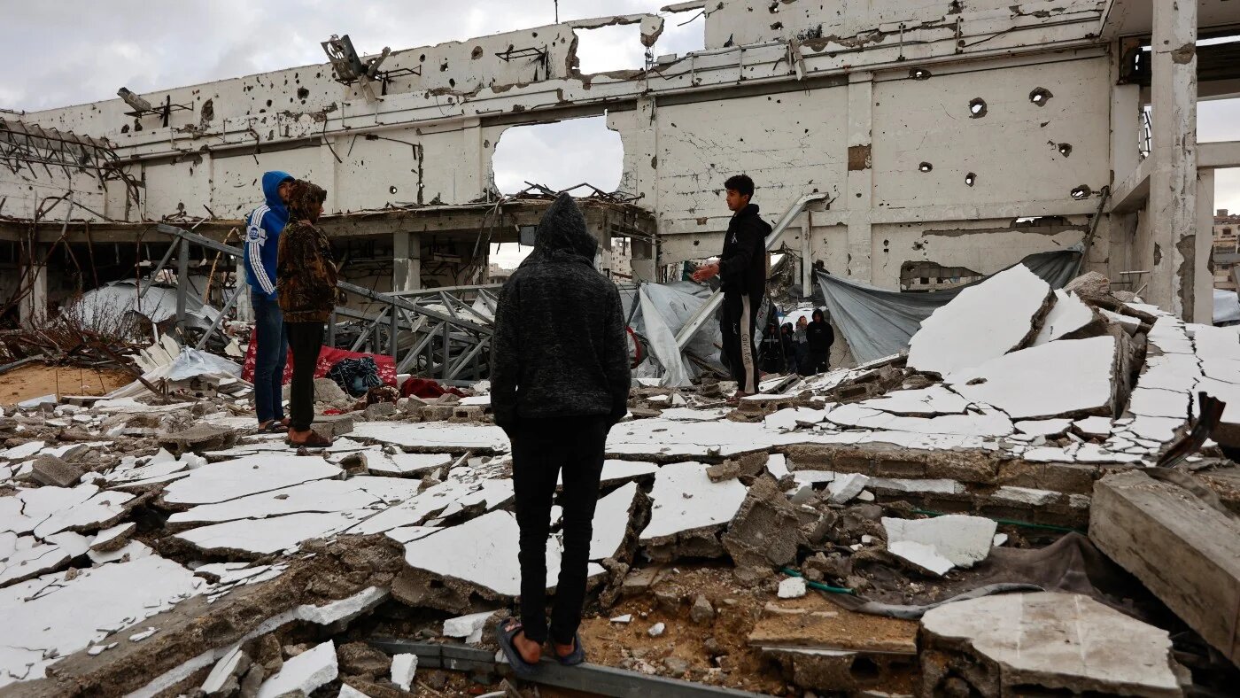 Palestinians stand amid the rubble inside a war-damaged building, parts of which collapsed on a windy winter day in Gaza City on 13 January 2026. Omar AL-QATTAA / AFP