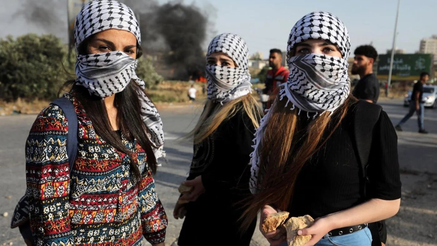 Des Palestiniennes masquées d’un keffieh traditionnel près de Ramallah en Cisjordanie occupée (AFP/Abbas Momani)