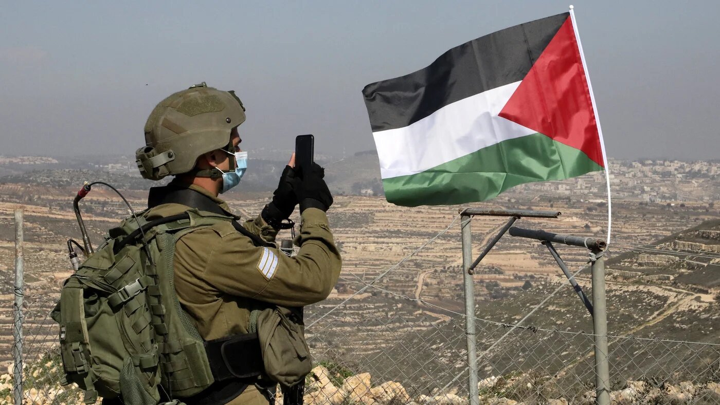 Israeli soldier stands near Palestinian flag in West Bank AFP