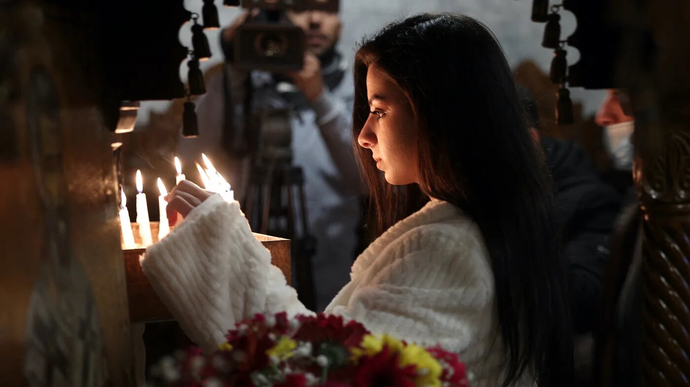 Une fidèle palestinienne allume un cierge lors d’une messe de Noël à l’église orthodoxe grecque Saint-Porphyre, à Gaza, le 7 janvier 2022 (AFP)