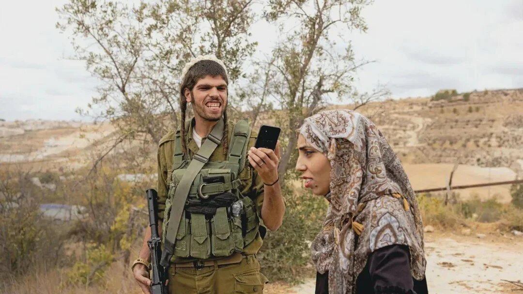 An armed Israeli settler films Meead Abu al-Rub in the occupied West Bank, 12 October 2025. The photograph, by Italian photographer Pietro Masturzo, featured on the front cover of L'Espresso magazine (Pietro Masturzo/L'Espresso)