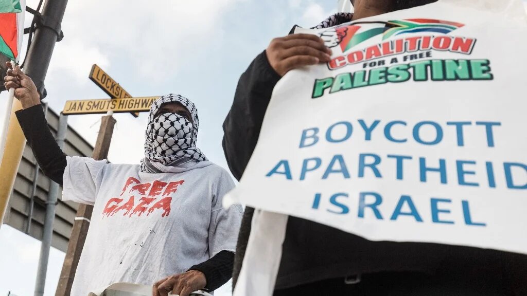 Pro-Palestinian supporters hold placards reading 'Boycott Apartheid Israel' during a protest to condemn the Israeli air strikes on Gaza, Durban, South Africa, 18 May 2021 (AFP)