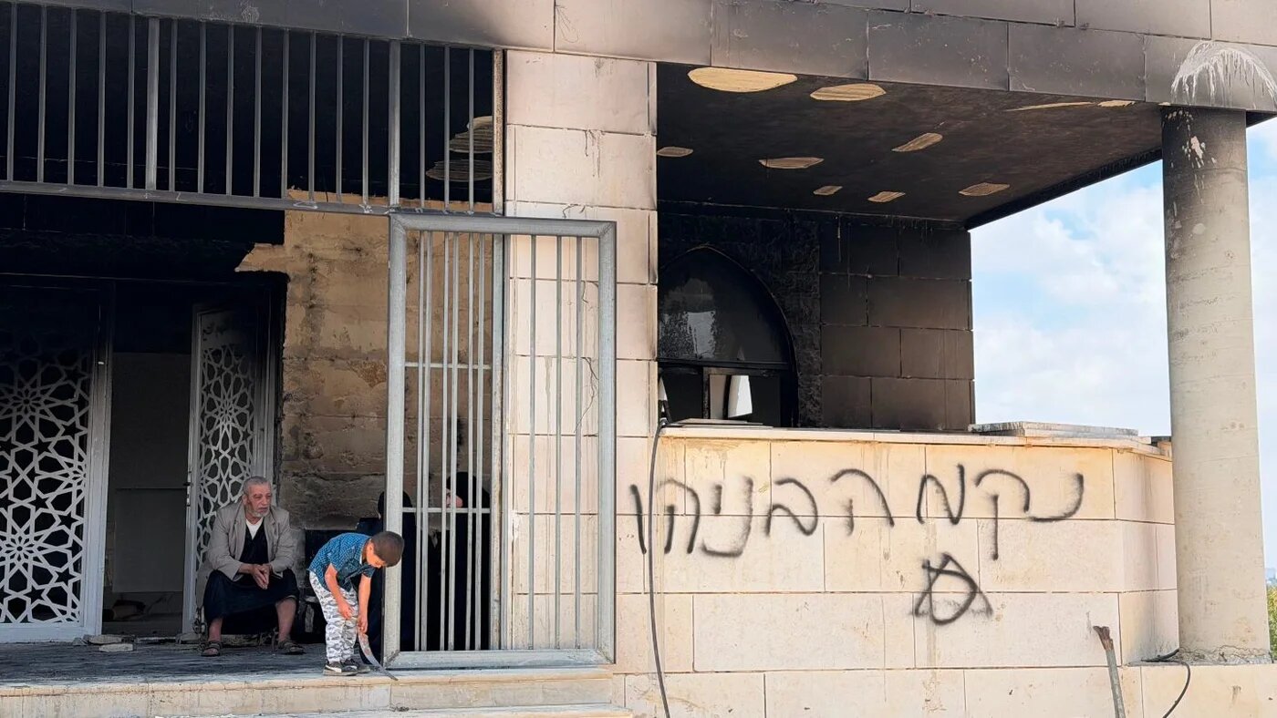 Residents inspect the fire-damaged al-Rahma mosque in Qusra, south of Nablus in the occupied West Bank, after an alleged settler arson attack (Muhammed Ateeq/Middle East Eye)