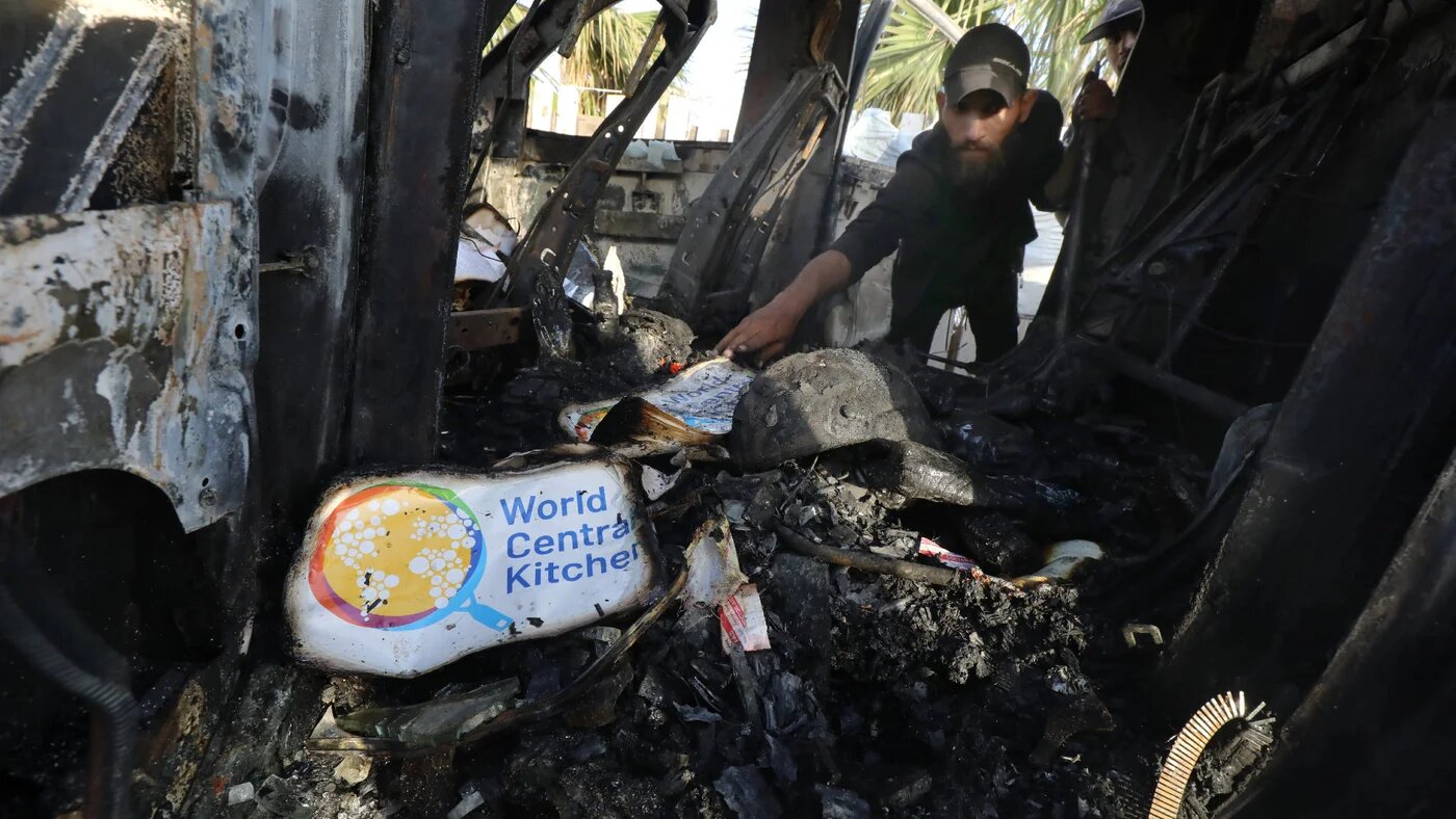 Palestinians inspect the heavily damaged vehicles belonging to World Central Kitchen after Israeli strikes attacks targeted the US-based aid group the previous day in Deir el-Balah, Gaza Strip, on 2 April (Omar Ashtawy/Reuters)
