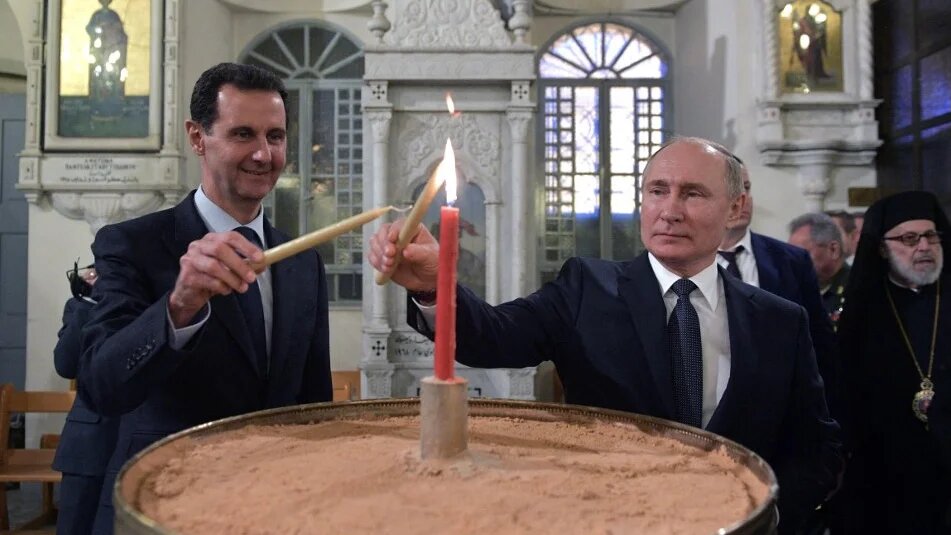Russian President Vladimir Putin (R) and Syrian President Bashar al-Assad (L) visit the Mariamite Cathedral of Damascus, in the Syrian capital, 7 January 2020 (AFP)