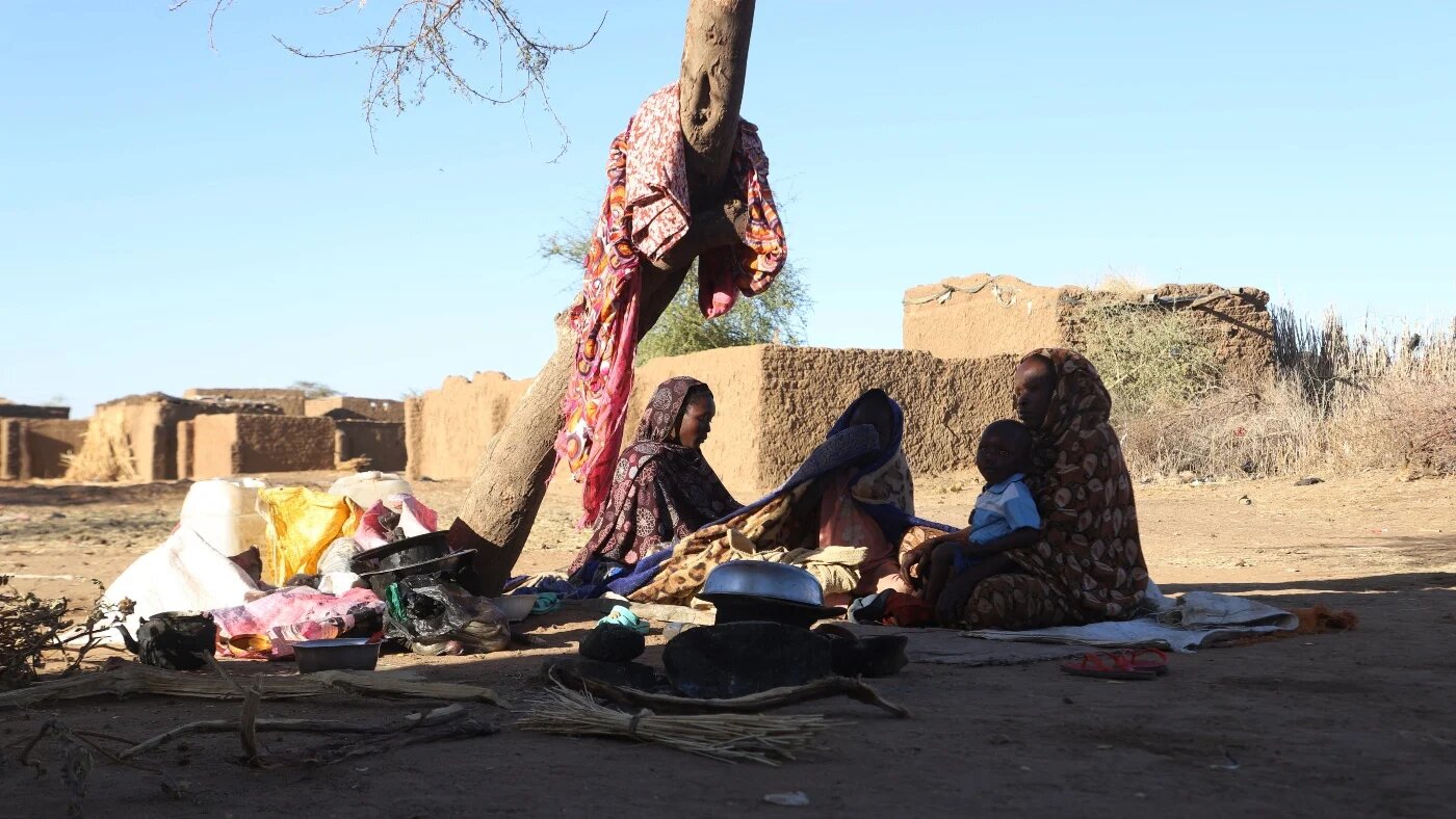 Sudanese displaced people who left el-Fasher after its fall, sit in the shade in Tawila at the Rwanda camp reception point on 17 December 2025 (AFP)