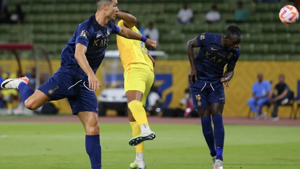Al-Nassr's Sadio Mane (R) heads the ball as teammate Cristiano Ronaldo (L) looks on during the Saudi Pro League match against Al-Hazem at the King Abdullah Sports City, Buraidah, 2 September 2023 (AFP)