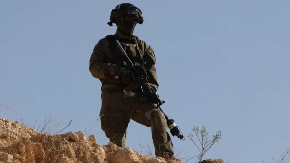 An Israeli soldier holds a position after Palestinian farmers’ olive harvest was disrupted by settlers and halted by Israeli security forces in Sa'ir village, near the Israeli occupied West Bank city of Hebron, on October 23, 2025.