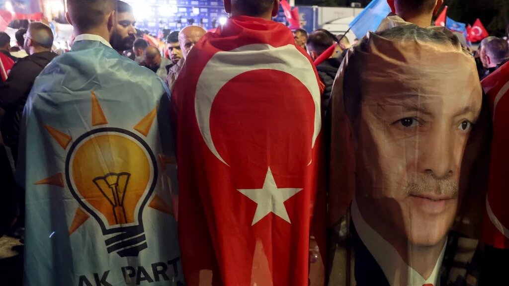 Supporters draped in the flags of the AK Party, Turkish flag and image of Turkish President Erdogan outside AK Party headquarters in Ankara, 15 May 2023 (AFP)