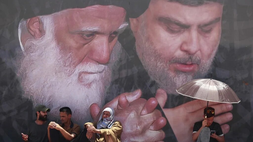 Des partisans de Moqtada al-Sadr assistent à la prière du vendredi sous une fresque représentant le leader chiite (à droite) à Sadr City, à l’est de Bagdad, le 17 juin 2022 (AFP)
