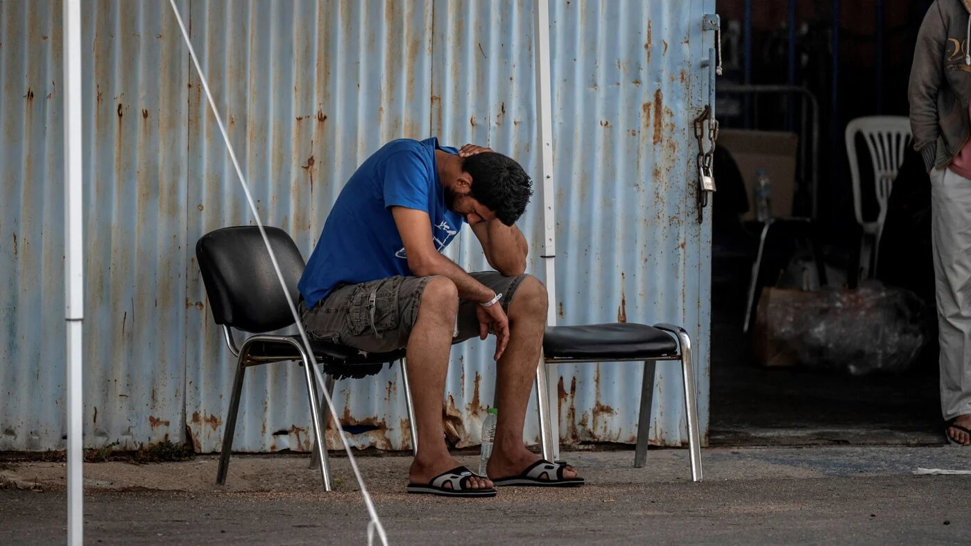 Survivors of a shipwreck stand at a warehouse at the port in Kalamata town, 15 June 2023 (AFP)