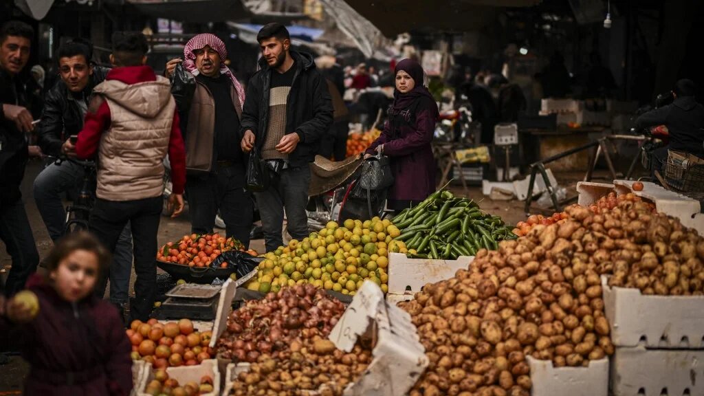 People walk past stalls at a street market in the town of Douma, on the outskirts of the Syrian capital Damascus on December 21, 2024. (Aris Messinis /AFP)