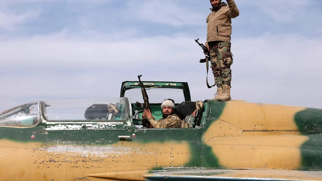 Anti-government fighters check a Syrian army jet after they took over a military airbase near the central city of Hama, on 6 December 2024 (Omar Haj Kadour/AFP)