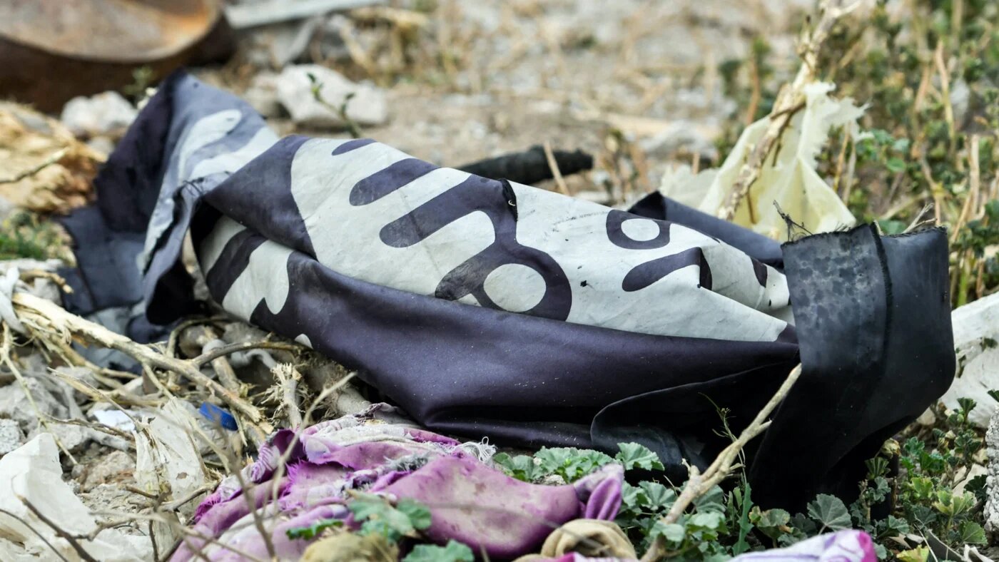 This picture taken on 24 March 2019 shows a discarded Islamic State flag lying on the ground in the Syrian village of Baghouz, a day after the group's 'caliphate' was declared defeated (AFP)