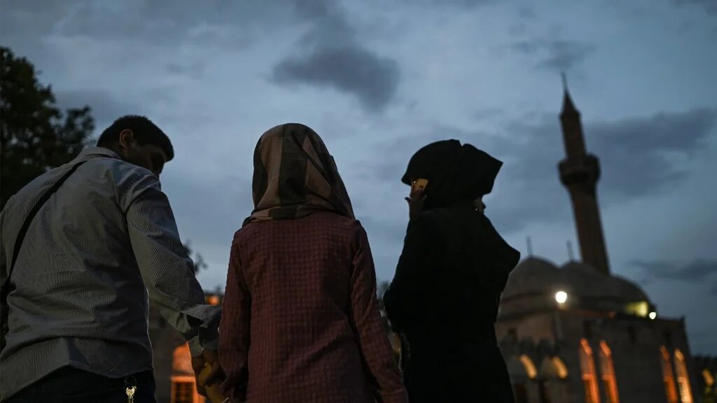 Une famille syrienne se promène près de Balıklıgöl (ou lac Halil-ur Rahman), au sud-ouest du centre-ville de Şanlıurfa, dans le sud-est de la Turquie, le 17 mai 2022 (AFP)