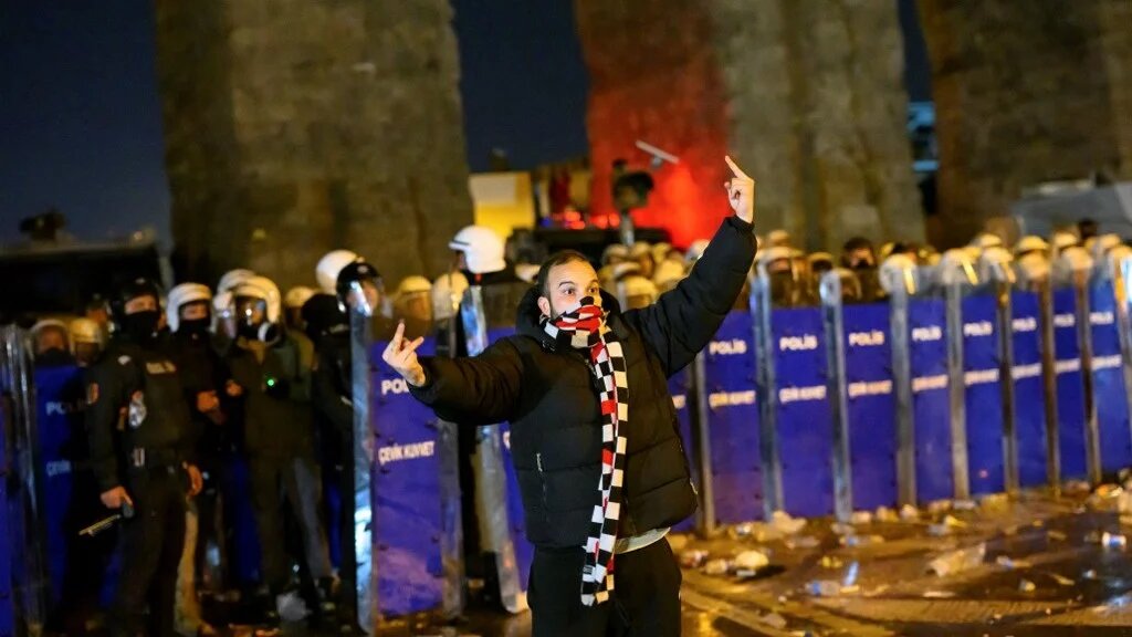 A photo taken by indicted photojournalist Yasin Akgul showing a protester gesturing in front of riot police at a demonstration following the arrest of Istanbul's mayor, near the city hall of Istanbul, on 21 March 2025 (Yasin Akgul / AFP)