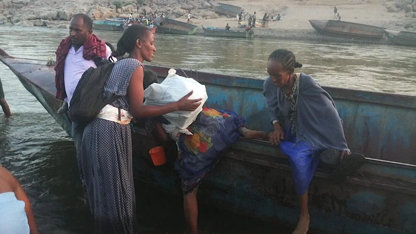 Des Éthiopiens fuyant la région du Tigré descendent d’un bateau après avoir traversé la frontière pour arriver à Hamdayet, leur point d’entrée au Soudan (MEE/Mohammed Amin)