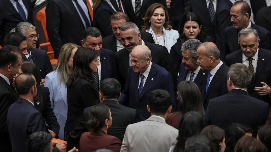 Turkish Nationalist Movement Party's (MHP) leader Devlet Bahceli (C) shake hands with Pervin Buldan (C-L), MP of Equality and Democracy (DEM) Party after voting a bill offering limited amnesty for Kurdish PKK militants at Grand National Assembly of Turkey in Ankara on August 10, 2026. (Adem Altan / AFP)