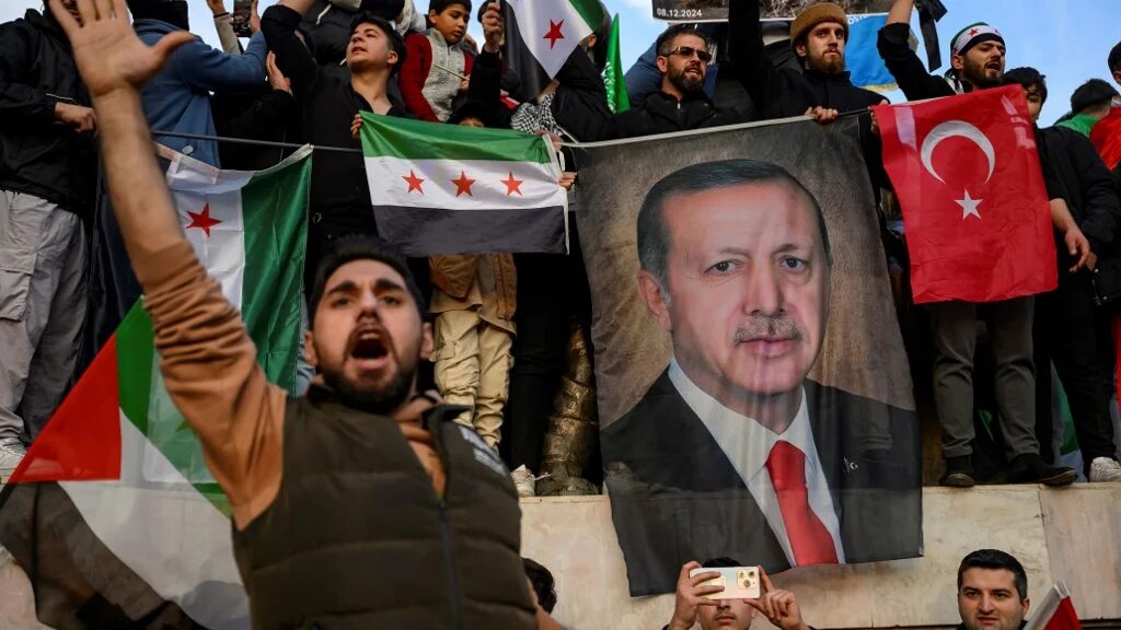 People hold a banner featuring Turkish President Recep Tayyip Erdogan as members of the Syrian community and supporters gather to celebrate the fall of Syrian president Bashar al-Assad in the face of an offensive by Islamist-led rebels, in Istanbul on December 8, 2024.  (Yasin Akgul / AFP)