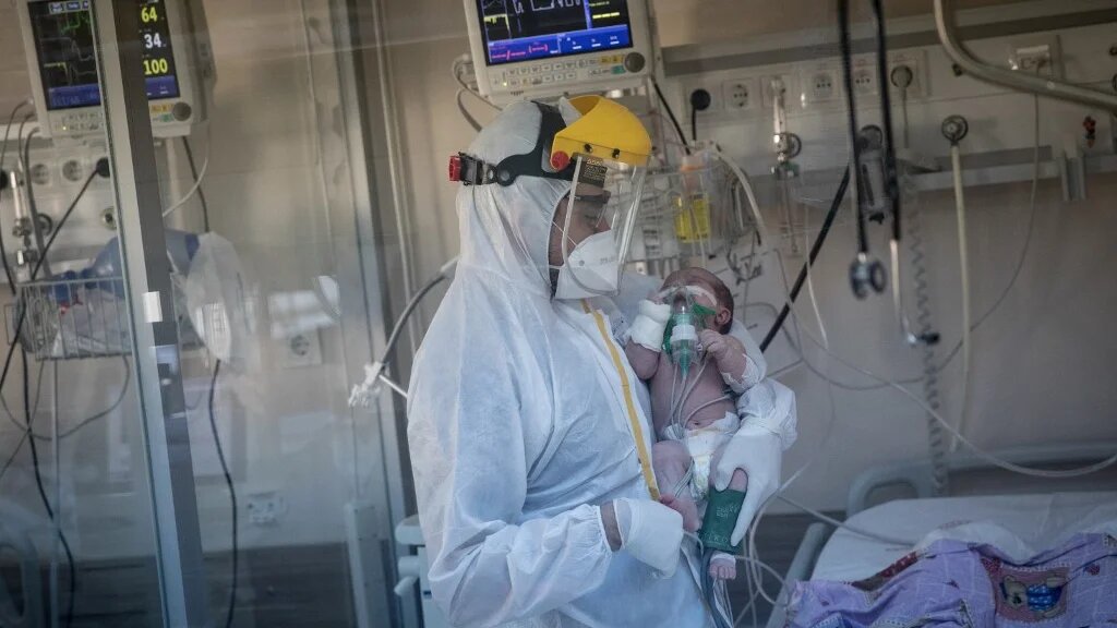 A medical worker assists a COVID-19 positive baby at a hospital Intensive Care Unit (ICU) on May 07, 2020 in Istanbul, Turkey. (Chris McGrath/ Getty Images via AFP)