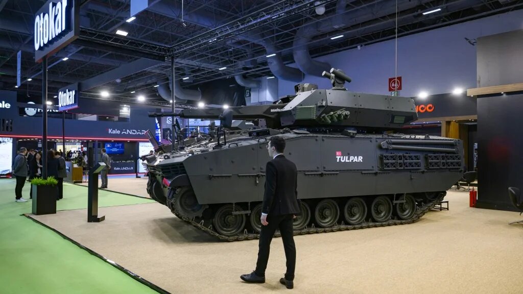 A man walk stand next to a Tulpa Turkish heavy infantry fighting vehicle during the opening day of the SAHA EXPO, an International Defence and Aerospace exhibition, in Istanbul on May 5, 2026. (Yasin AKGUL / AFP)
