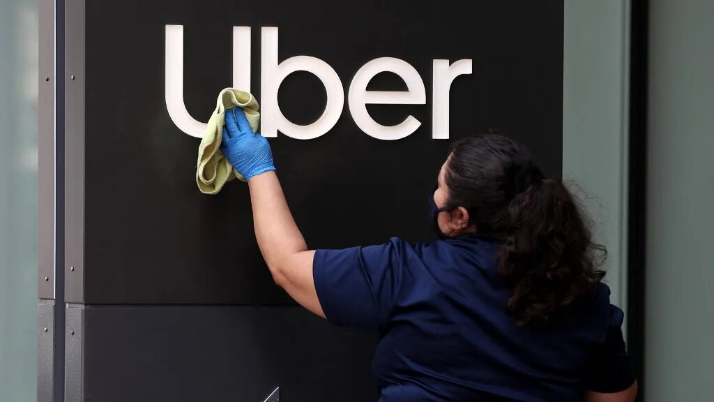 Une employée nettoie l’enseigne d’Uber, au siège de l’entreprise, le 18 mai 2020 à San Francisco, Californie (AFP)