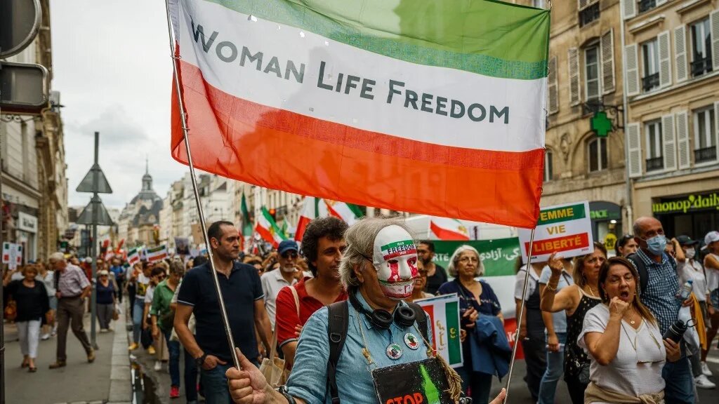 A demonstrator carries a flag displaying with the colours of the Iranian flag reading "Woman Life Freedom" in Paris on 16 September, 2023 (Dimitar Dilkoff/AFP)