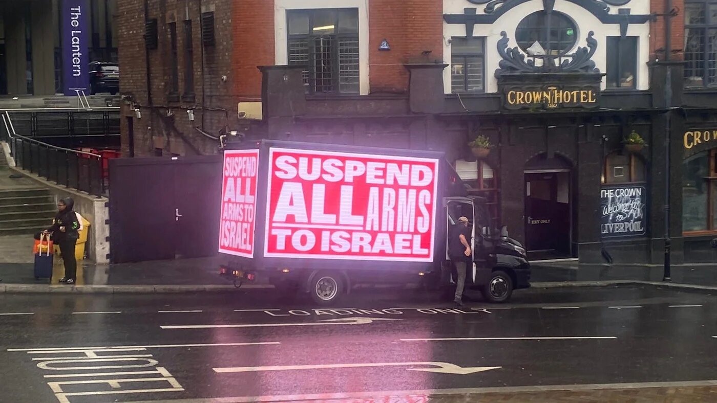 A van displaying a poster reading 'Suspend all arms sales to Israel' parks outside the Labour conference in Liverpool (Dania Akkad)