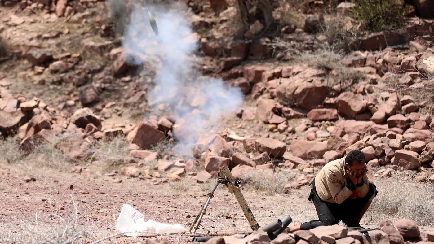 A fighter loyal to Yemen's Saudi-backed government launches a mortar during clashes with Houthis near Taiz
