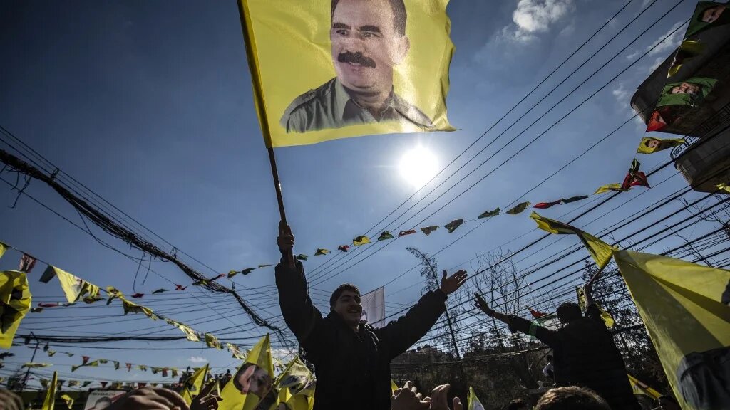 A protester waves a flag bearing a portrait of Abdullah Ocalan, the leader of the Kurdistan Worker's Party (PKK), during a demonstration in the city of Qamishli in northeastern Syria on 15 February 2025 (AFP/Delil Souleiman)
