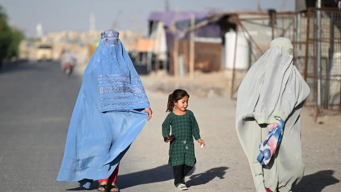 Afghan women along with a girl walk along a street in Loy Viala village in Afghanistan's Kandahar on 21 June 2026 (Sanaullah Seiam/AFP)