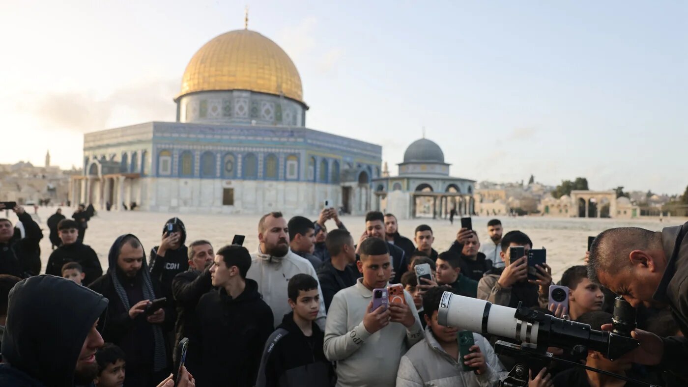 People watch as a man uses a telescope while searching for the crescent moon to mark the start of the Muslim holy fasting month of Ramadan, near the Dome of the Rock at Al-Aqsa mosque, in the Old City of Jerusalem on 17 February 2026 (AFP/Ahmad Gharabli)