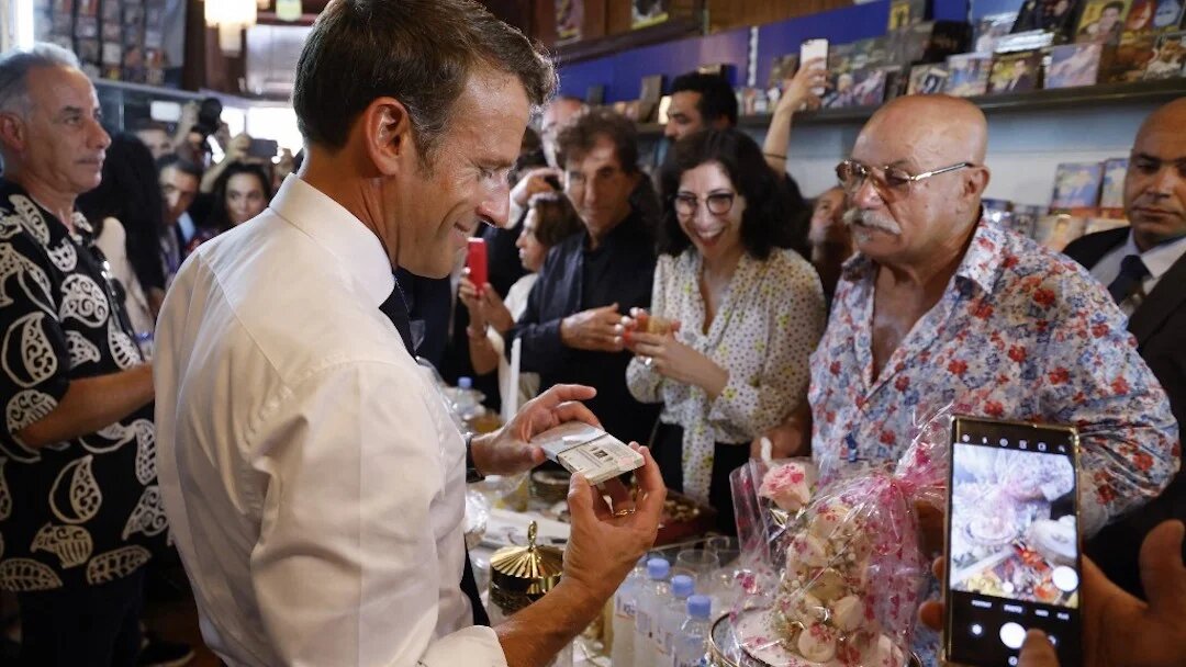 Le président français Emmanuel Macron visite Disco Maghreb, le label mythique de la musique raï, devant son propriétaire, Boualem Benhaoua (à droite), à Oran le 27 août 2022 (AFP/Ludovic Marin)