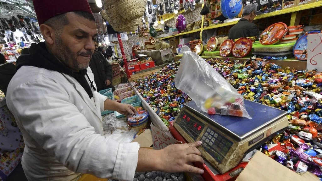 Un vendeur pèse une commande de bonbons dans sa boutique du centre-ville de Blida, au sud d’Alger, le 11 janvier 2024, alors que les gens se préparent à célébrer le Nouvel An amazigh (AFP)