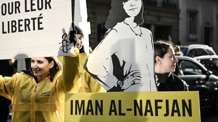 People hold a sign reading "honk for women's rights" and cutouts of a woman incarcerated during a demonstration organised by Amnesty International outside the Saudi embassy in Paris, on 8 March 2019