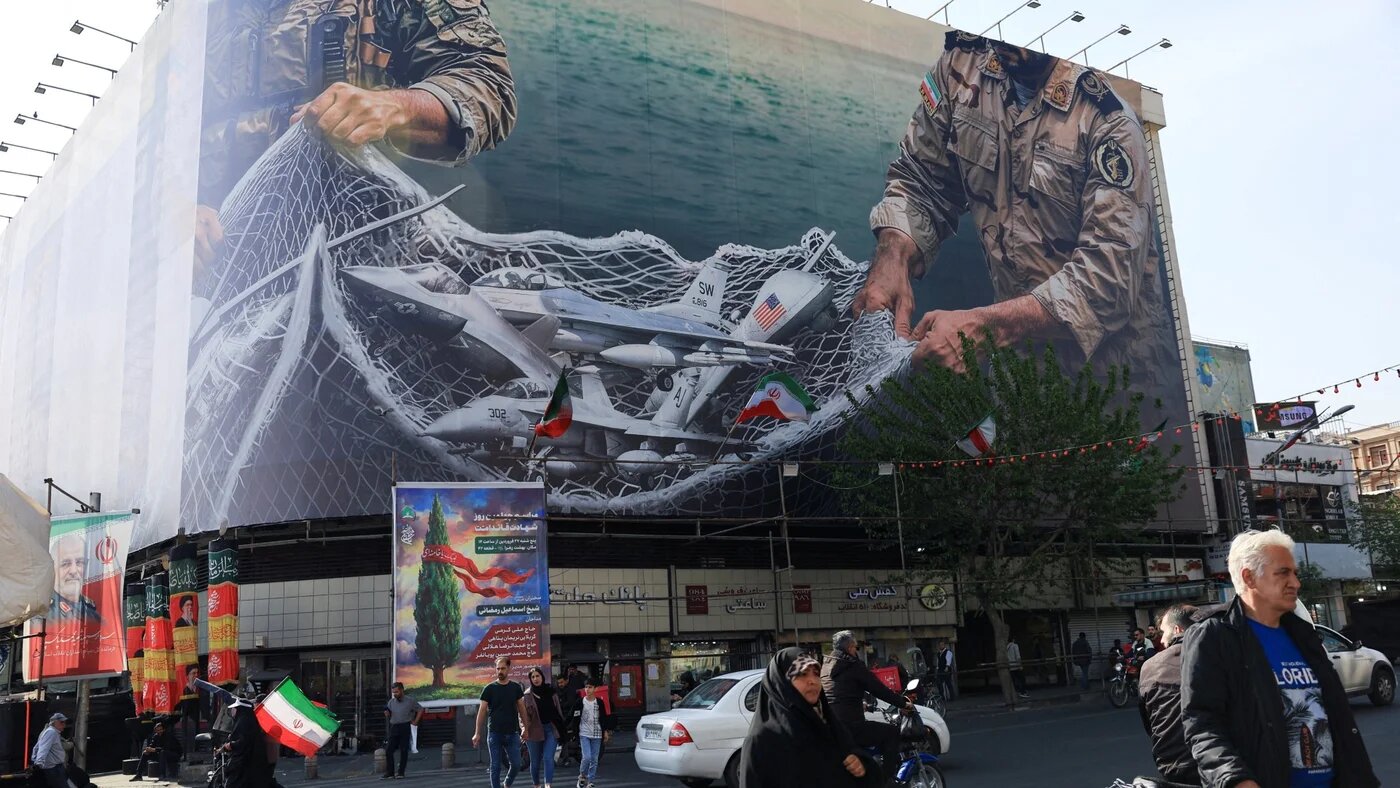 People walk near an anti-US billboard on a building in Tehran, Iran, on 16 April 2026 (Reuters/Thaier Al-Sudani)
