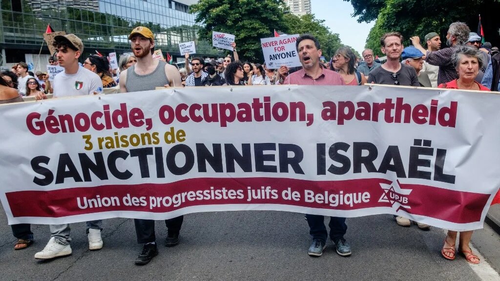 People hold a banner stating: “Genocide, occupation, apartheid, 3 reasons to sanction Israel” during a protest in Brussels, Belgium, on 11 May 2025 (Hatim Kaghat/Belga/AFP)