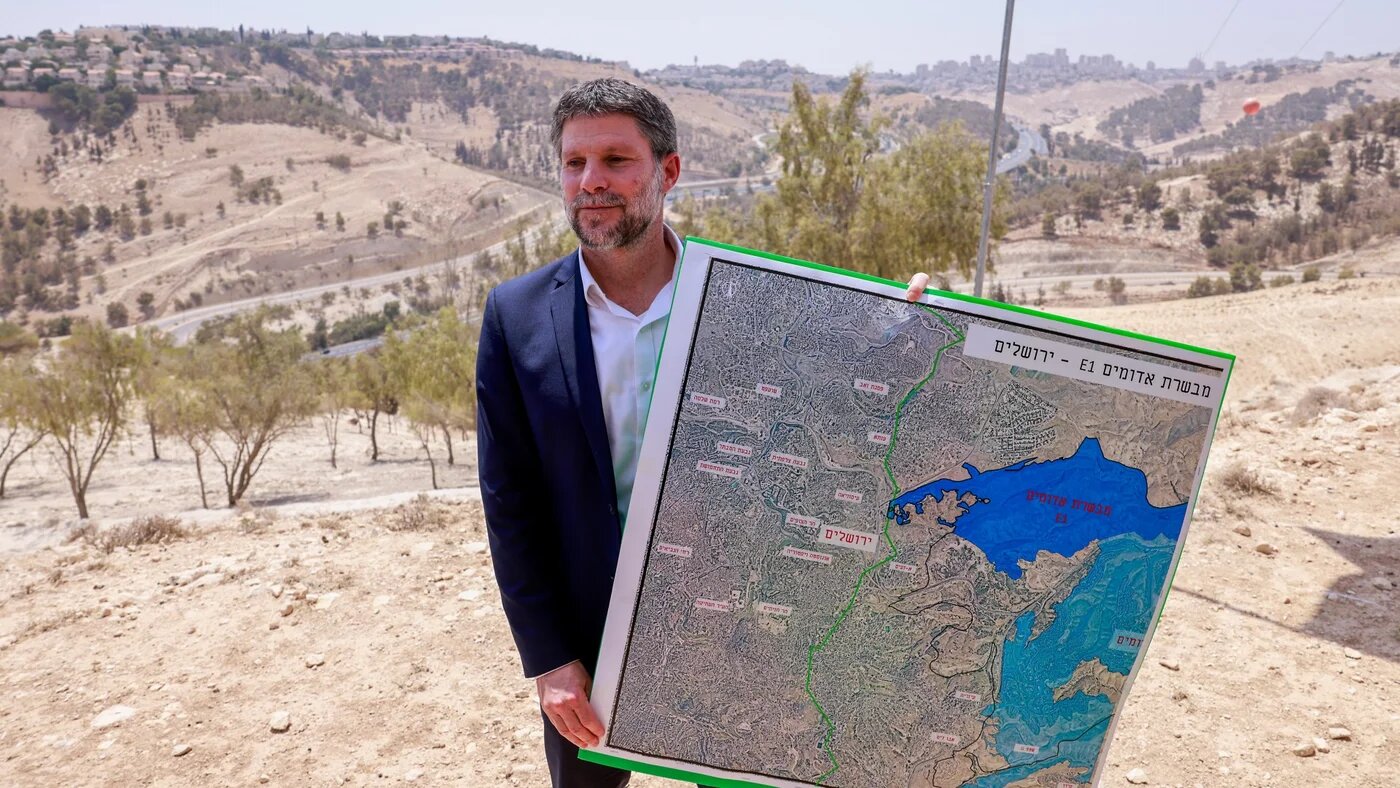 Israeli far-right Finance Minister Bezalel Smotrich holds a map of an area near the settlement of Maale Adumim, a land corridor known as E1, outside Jerusalem in the occupied West Bank, on 14 August 2025 (AFP/Menahem Kahana)