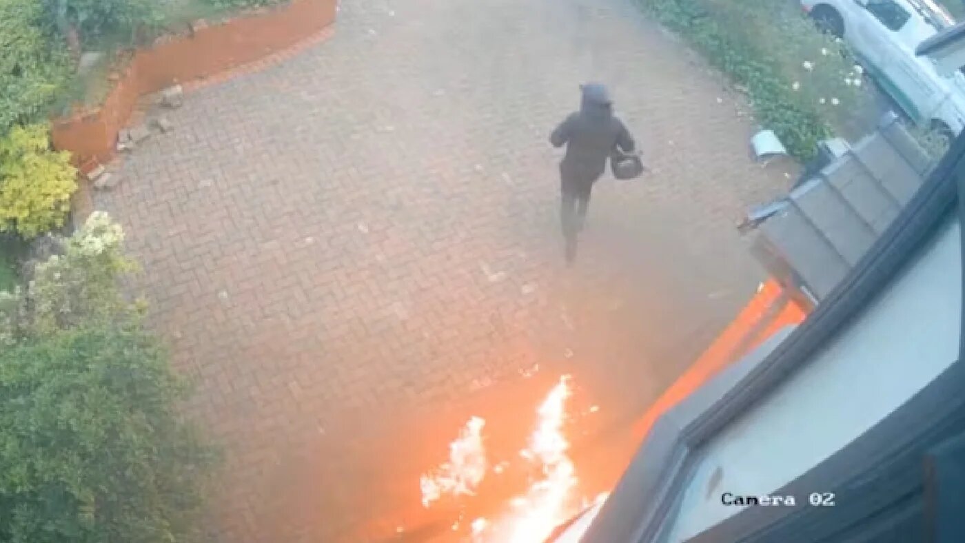 CCTV footage shows a man wearing a helmet and black clothing setting the home of Imam Hassan Patel on fire on 10 June 2026 in Bolton, northern England (CCTV/Screengrab)