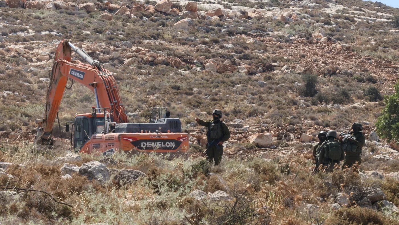 Israeli forces guard a bulldozer reportedly operating on Palestinian lands near the village of Dura, west of Hebron in the occupied West Bank, on 9 June 2026 (AFP/Hazem Bader)