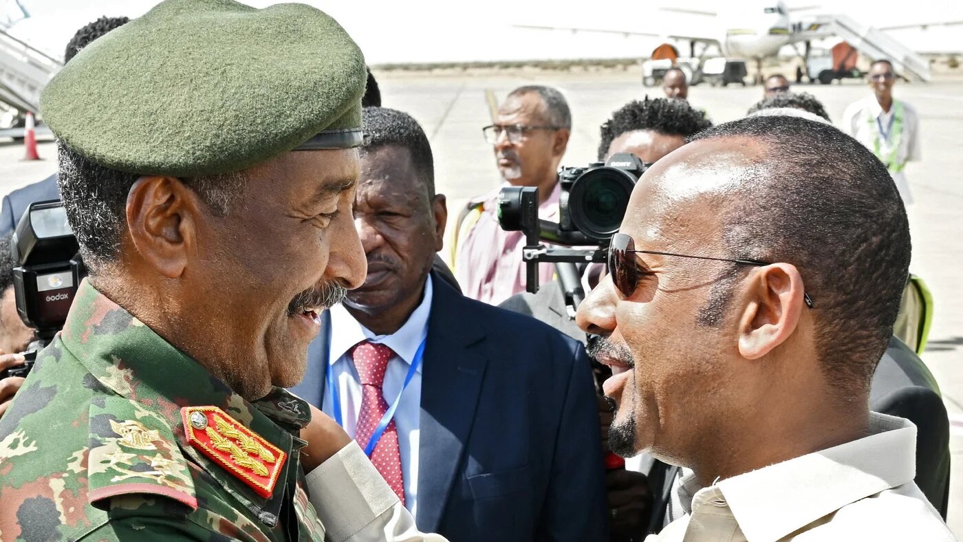 General Abdel Fattah al-Burhan (L) welcomes Ethiopia's Prime Minister Abiy Ahmed, as he arrives for an official visit at Port Sudan International Airport on 9 July (AFP)
